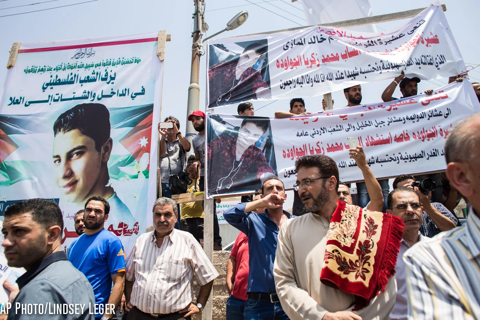 Placards are seen at the funeral of Mohammed al-Jawawdeh, a 17-year-old Jordanian, who was killed on Sunday evening by an Israeli security guard who said he was attacked by him with a screwdriver, on Tuesday, July 25, 2017 in Amman, Jordan. (AP Photo/Lindsey Leger)
