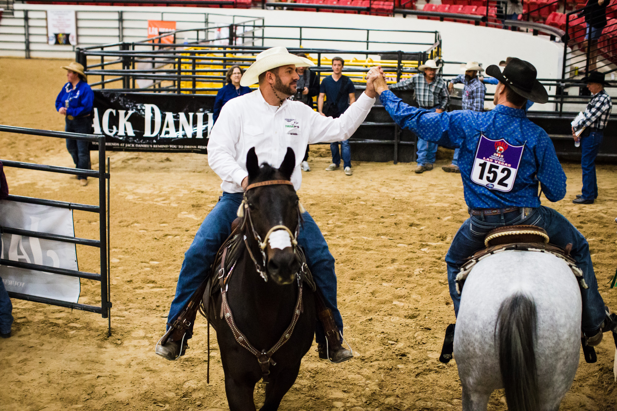 Two contestants congratulate each other during the Mounted Breakaway Roping, in which one team member must rope a steer around the head, and the other must rope one of its back legs, while riding a horse.