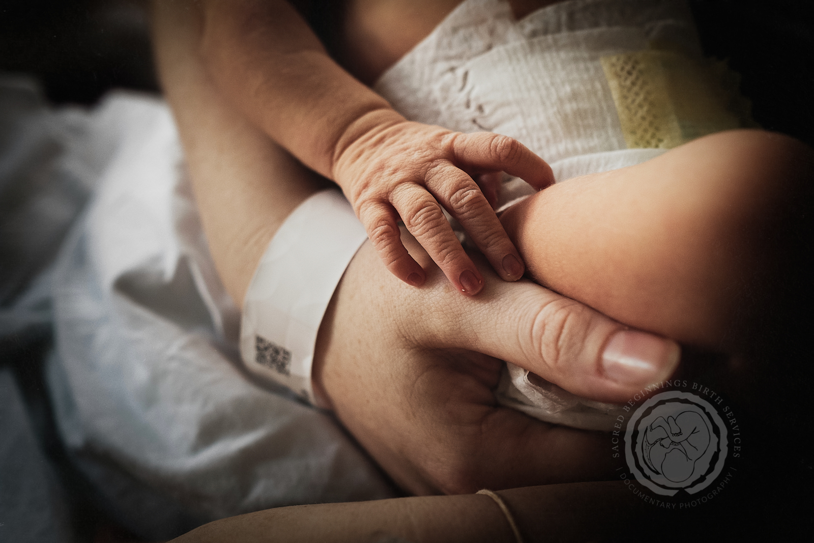 Mum and newborn baby hands together after their hospital birth near Derby, Derbyshire, UK.