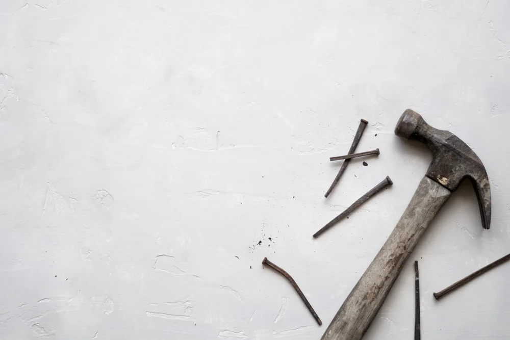 A carpenter's hammer and nails on a white surface