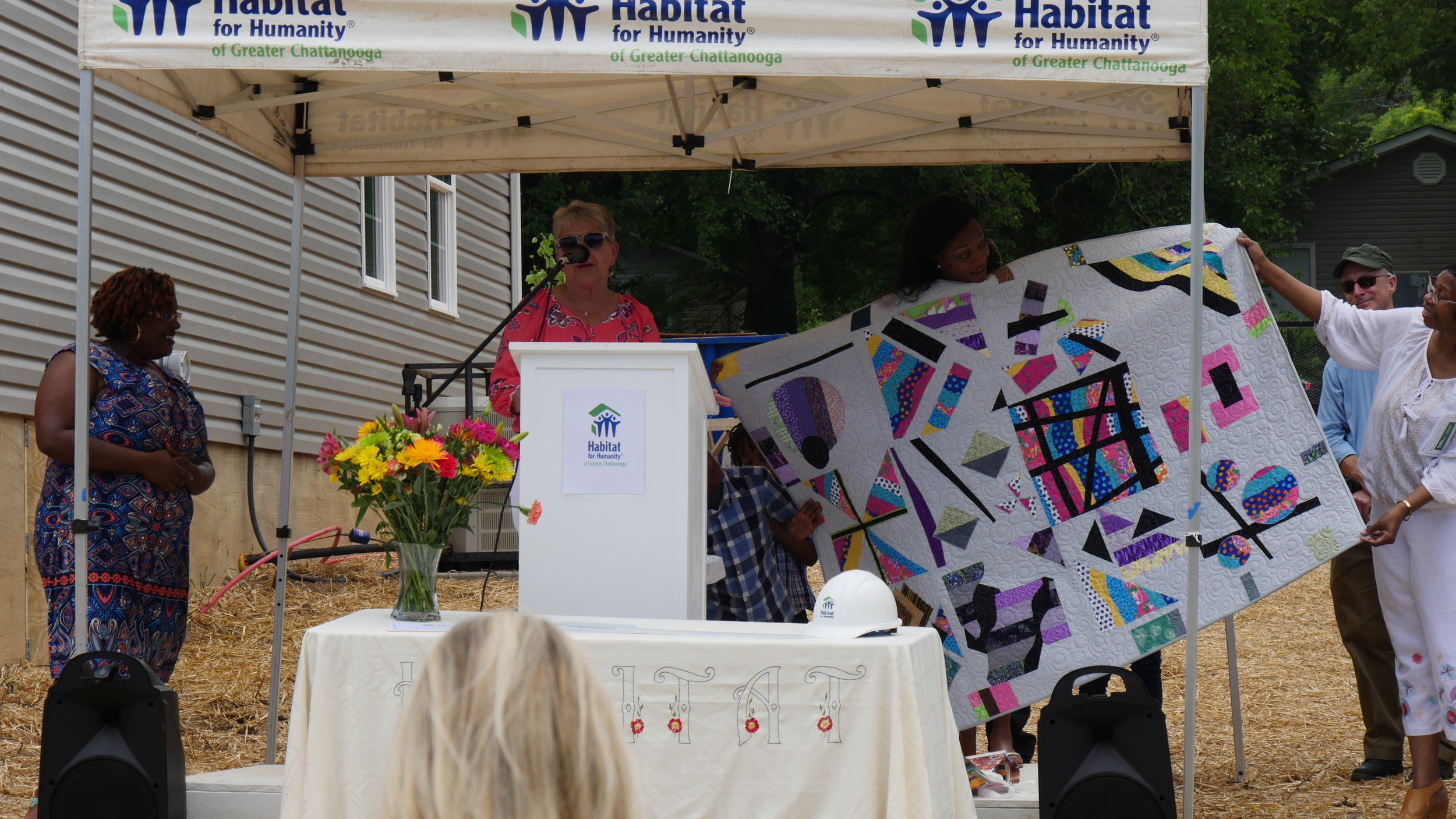 Sandi Suggs (behind podium) presents Ashley (center) with her quilt. Photo courtesy of Habitat for Humanity of Greater Chattanooga.
