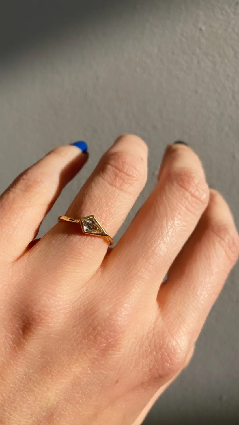 White diamond kite ring shown on a hand, glowing in the natural light.