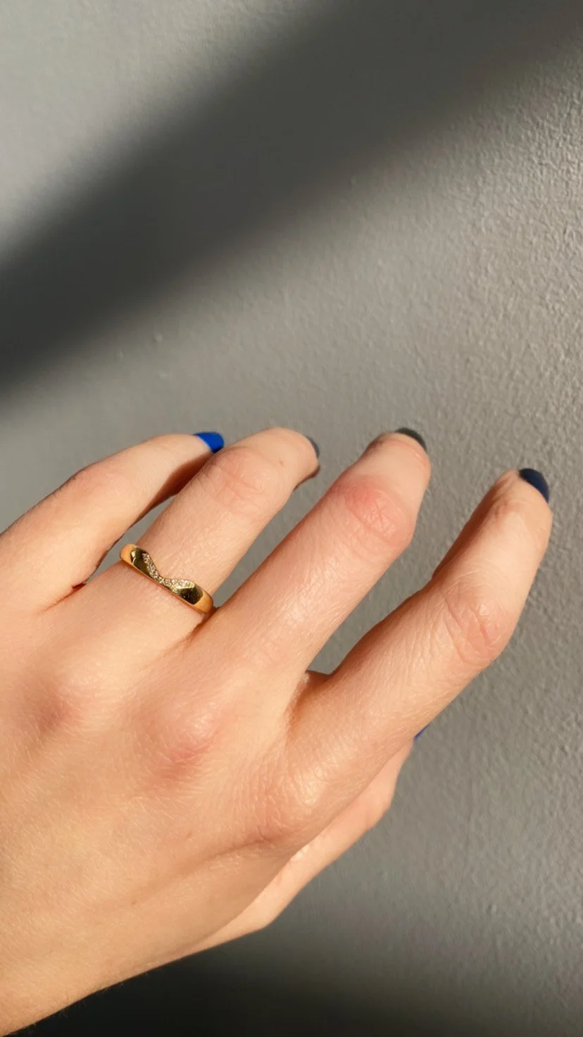 a hand wearing the Notch Halo Ring with white diamonds on the ring finger.