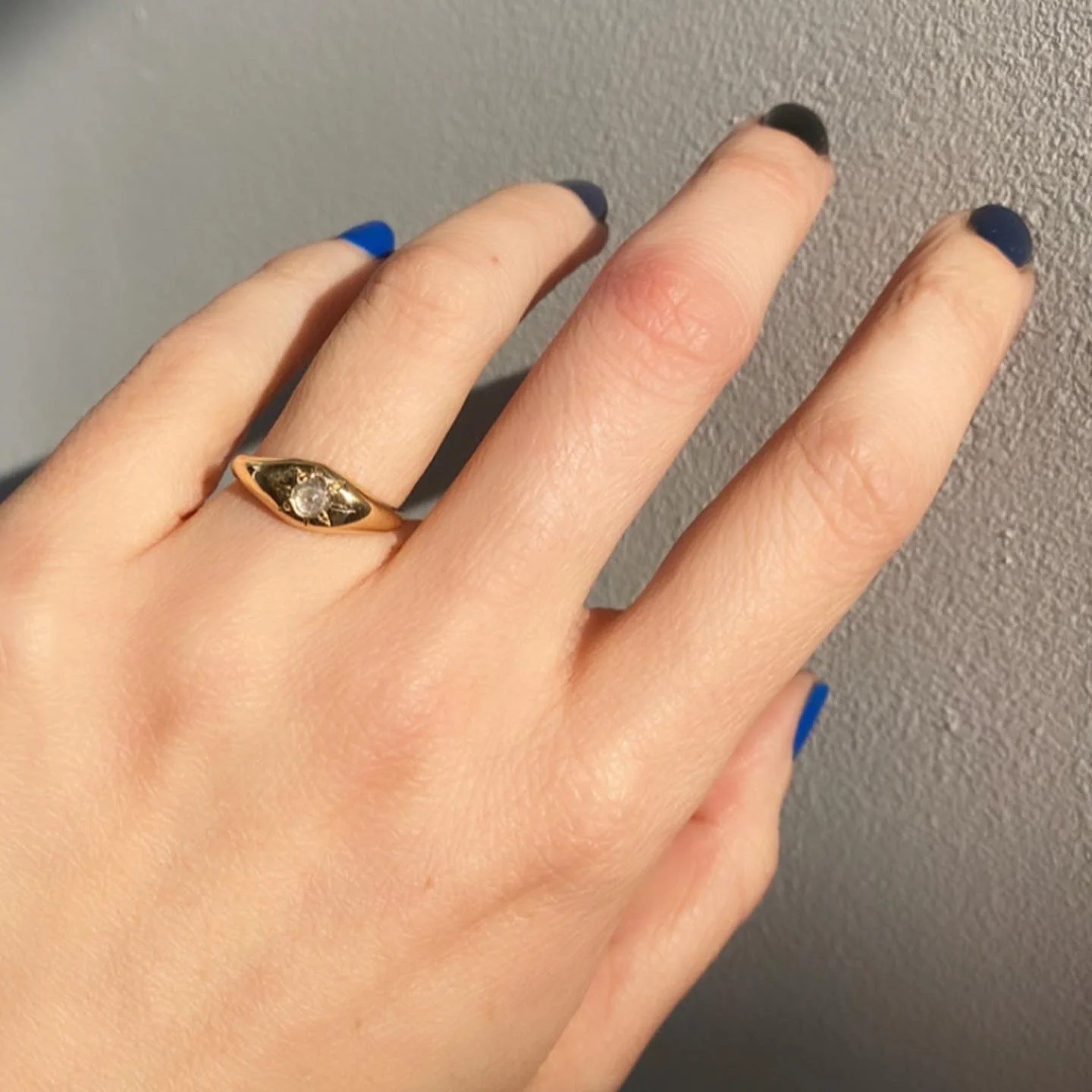 Hand with long, slim fingers wearing the True North Ring in dramatic lighting.