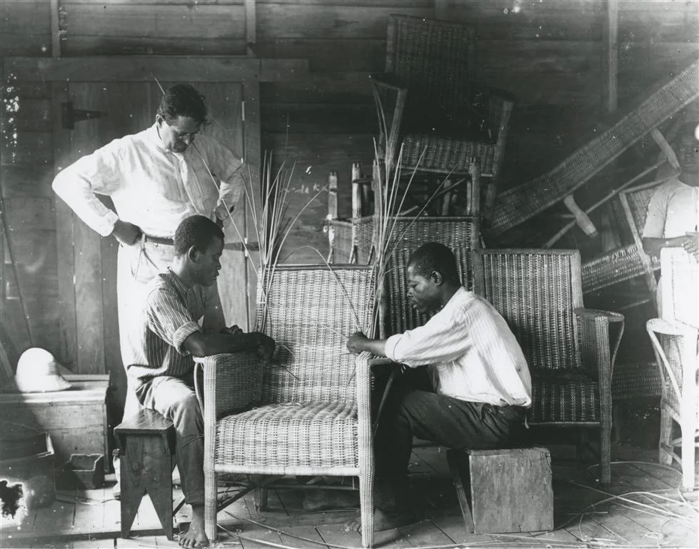 My grandfather and two students in the furniture-making class. On the left you see his pith helmet.