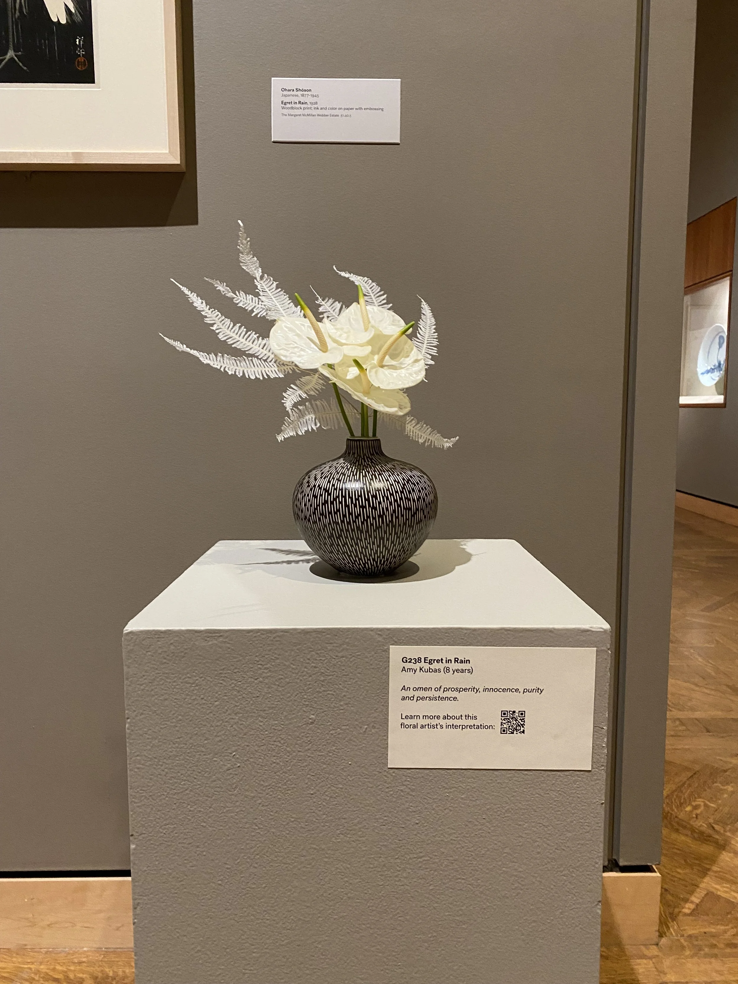White floral arrangement in sgraffito vase placed upon a pedestal