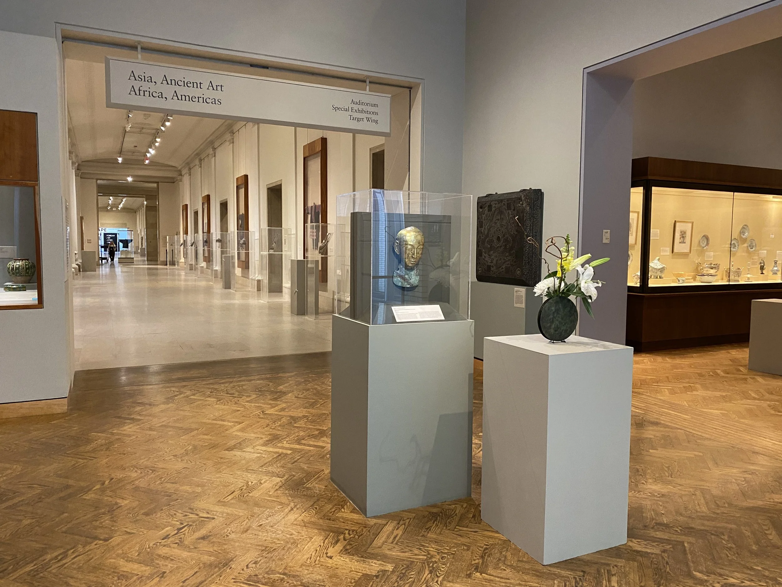 flowers arranged on a pedestal next to a bronze funerary mask