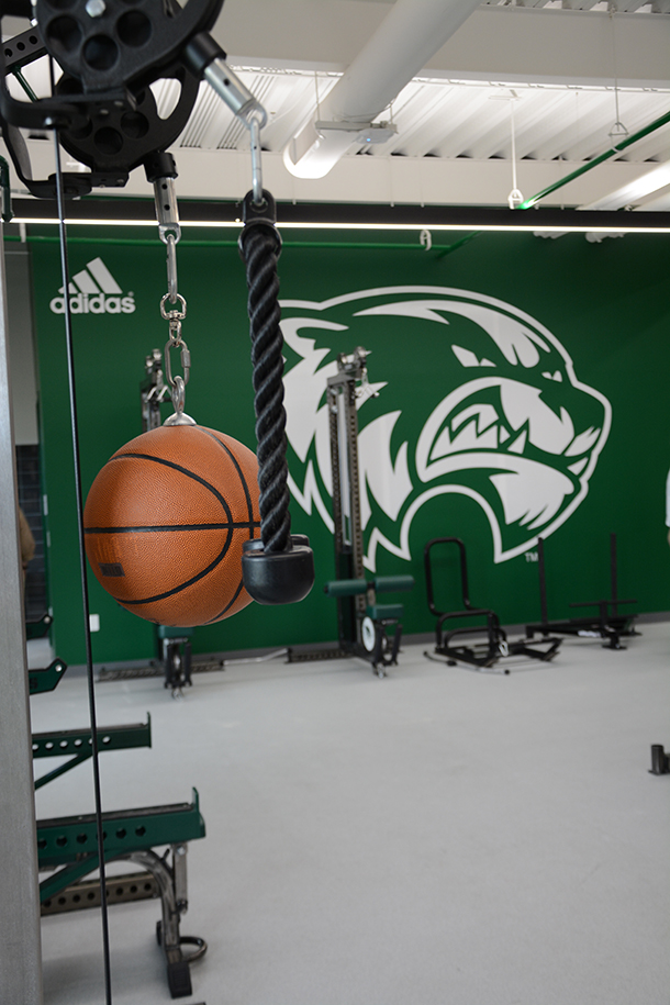 The Travis Hansen Strength & Conditioning Center has a net mesh separating the weight room from the basketball court. 
