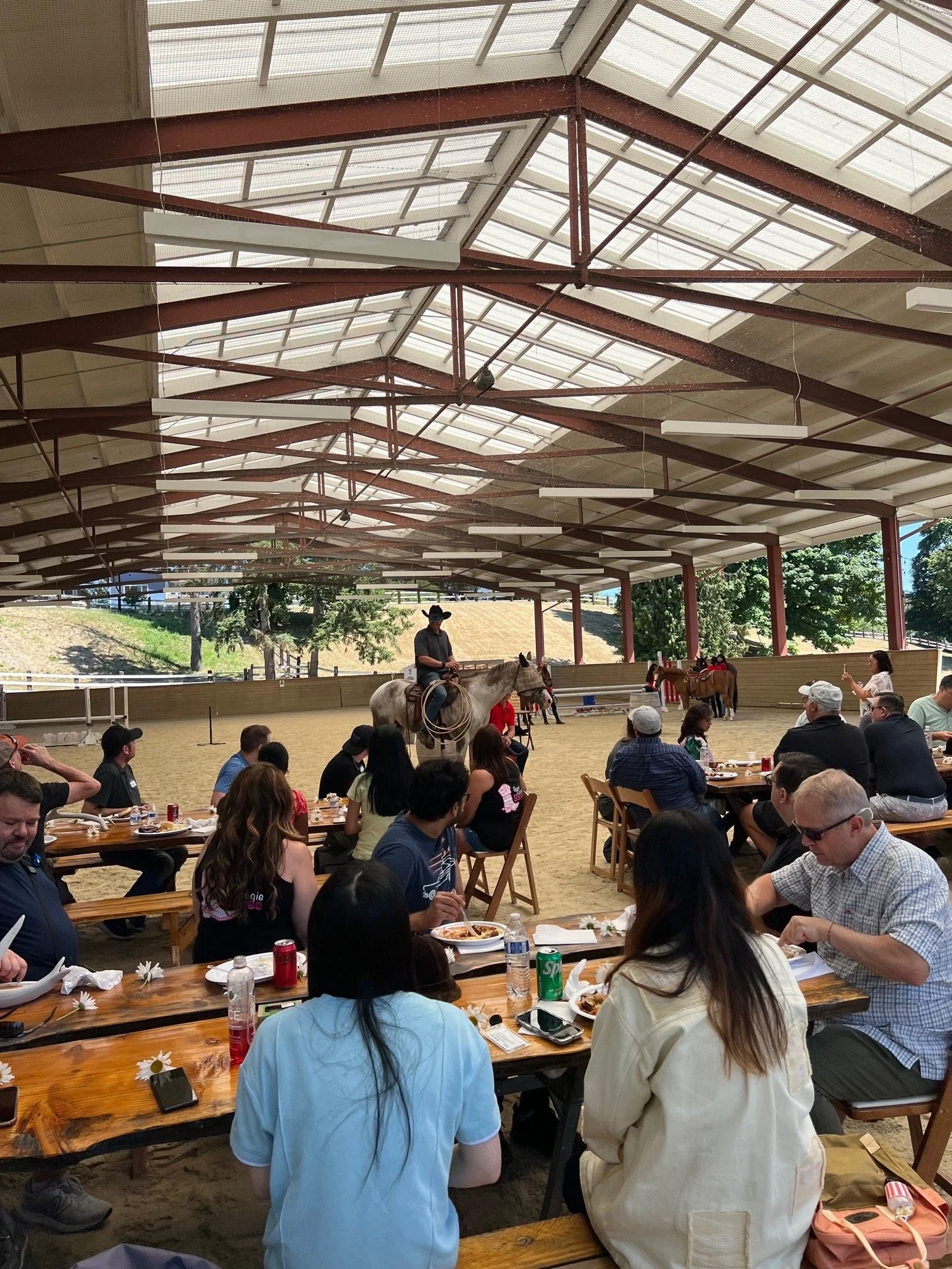Indoor rodeo event with people sitting at tables and a person riding a horse in the arena