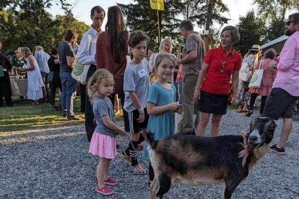 Families and children enjoying Seattle Farm's upcoming events with farm animals including a goat at the historic Washington State farm
