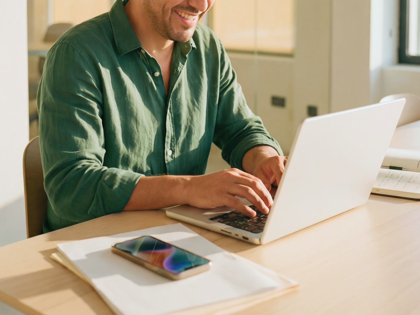Group of five diverse young adults collaborating around a laptop in a modern office, smiling and engaged with their work.