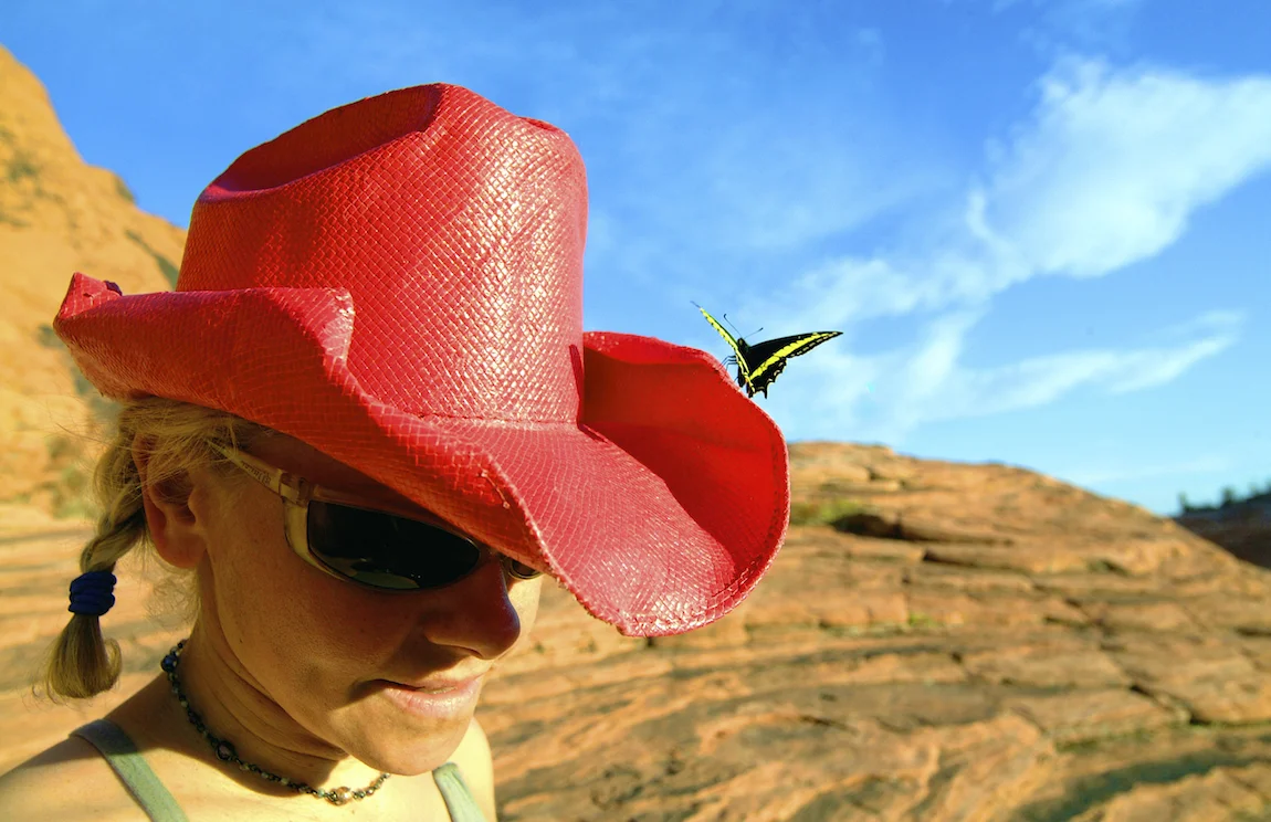 A butterfly lands on the red cowboy hat of a climber in Red Rock Canyon, Nevada. Image by New Orleans based travel photographer, Marc Pagani - marcpagani.com