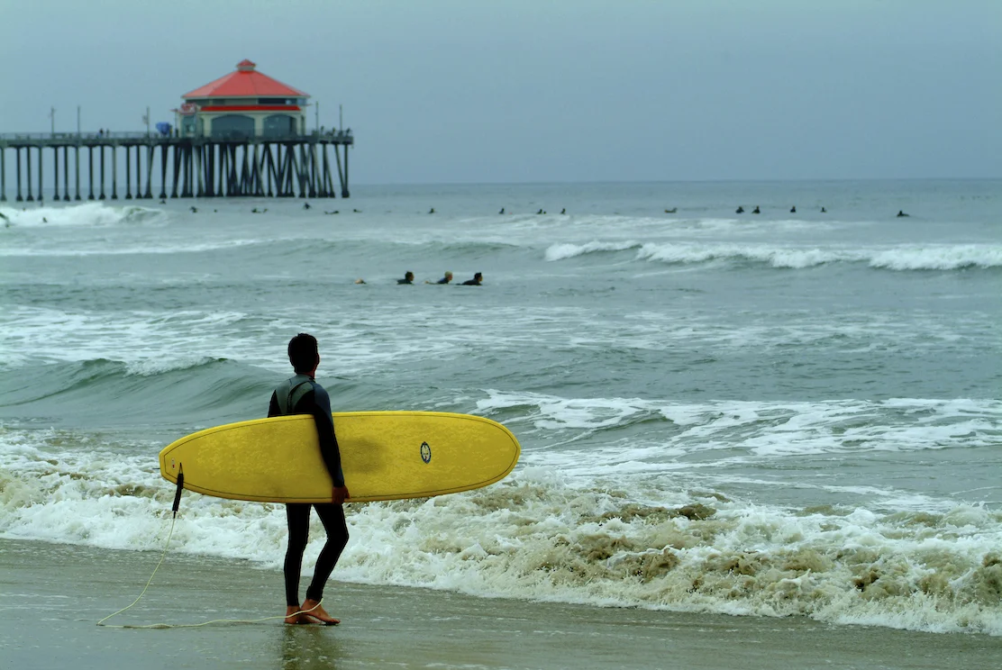 A surfer looks at the waves at Huntington Beach, California. Image by New Orleans based travel photographer, Marc Pagani