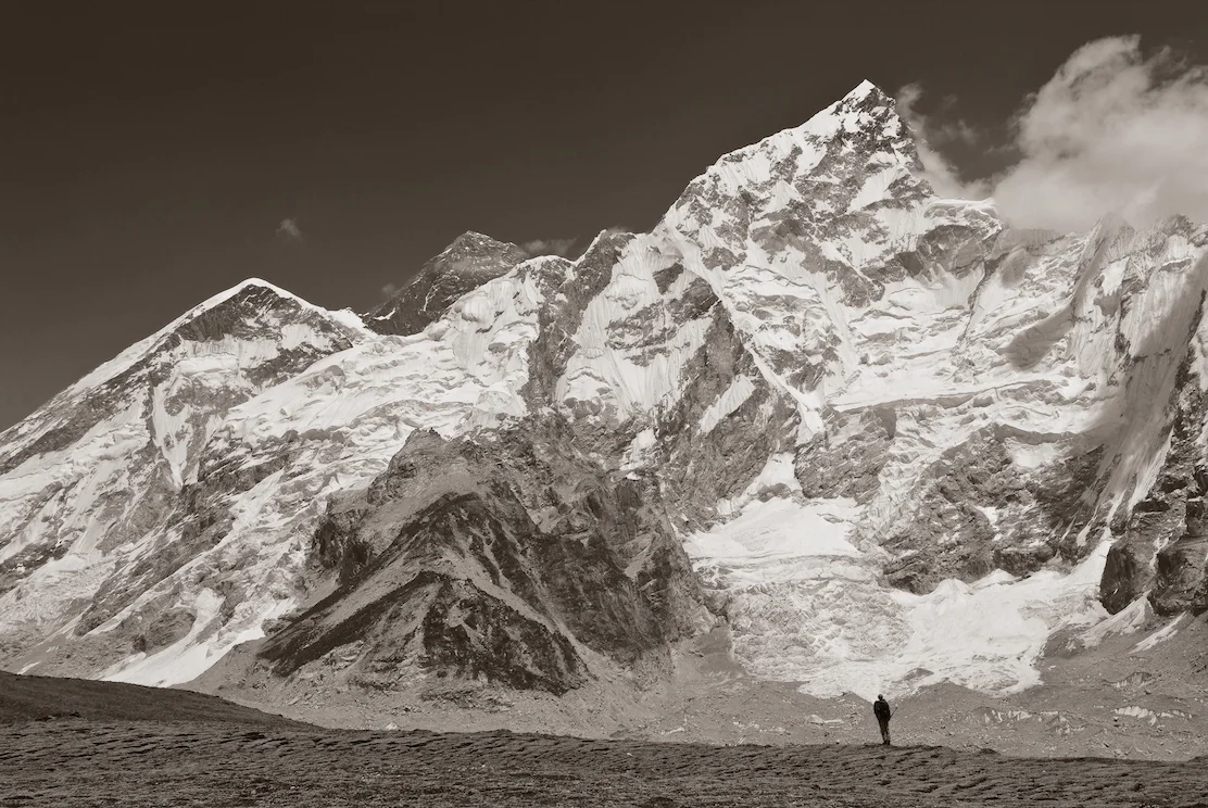 A climber stands in front of Ama Dablam and Mount Everest after climbing Kala Pattar in the Nepal Himalayas. Image by New Orleans based travel photographer, Marc Pagani - marcpagani.com