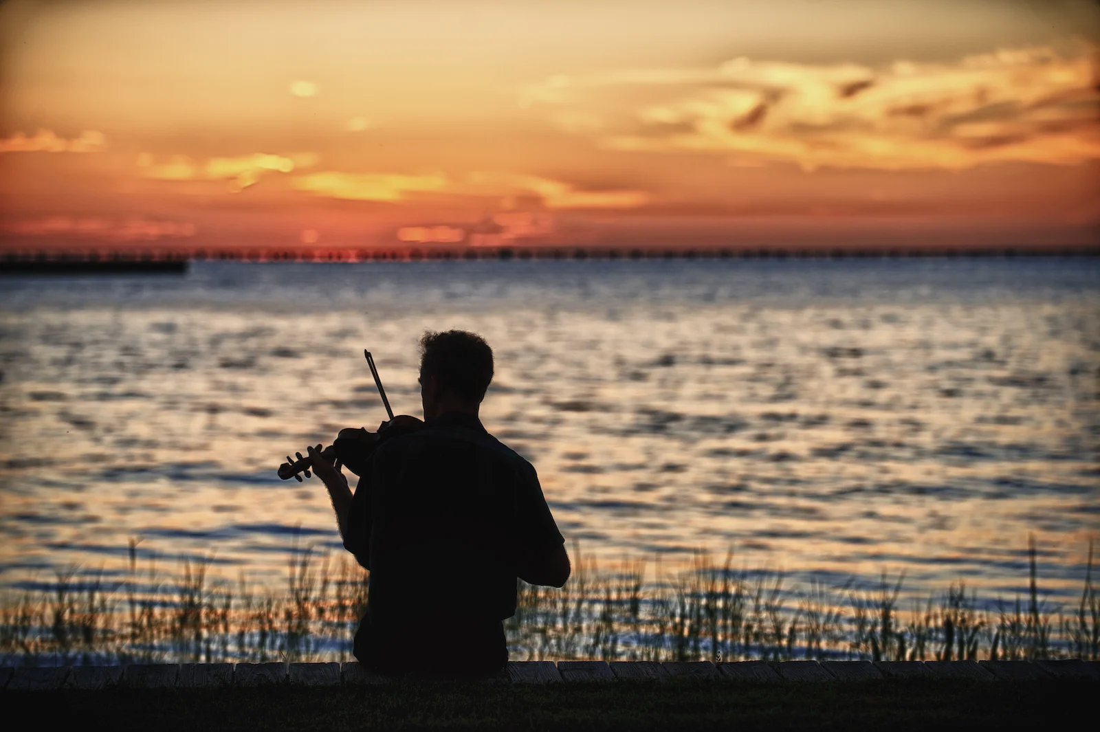 A mand plays fiddle on the north shore of Lake Pontchartrain in Louisiana. Image by New Orleans based travel photographer, Marc Pagani