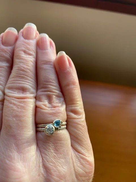 Gemstone ring stack with diamond ring and emerald teardrop stone. 