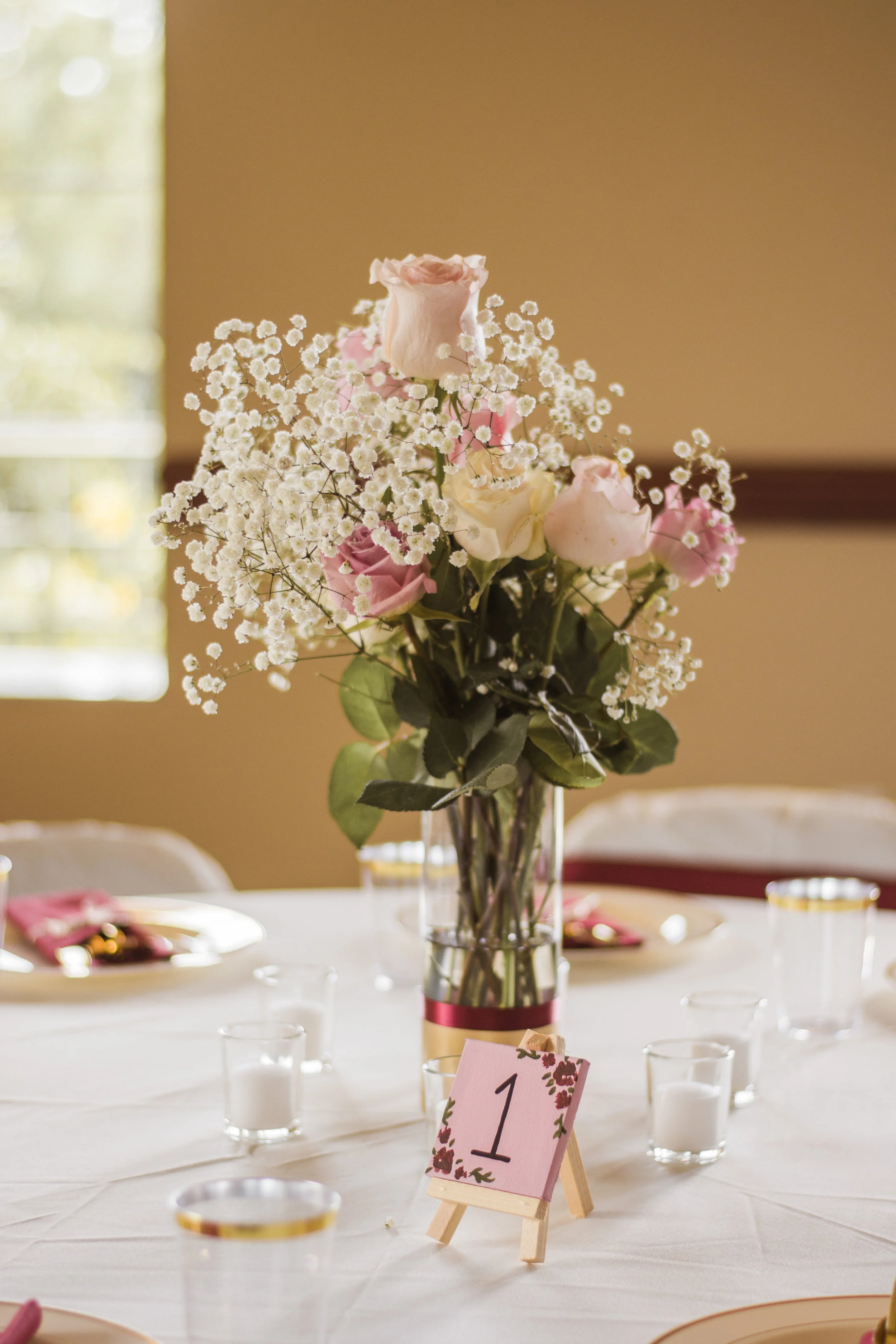 Pictured above are the flowers we arranged ourselves, alongside a table number we painted. We found the surrounding votive candles on sale and ordered them online.