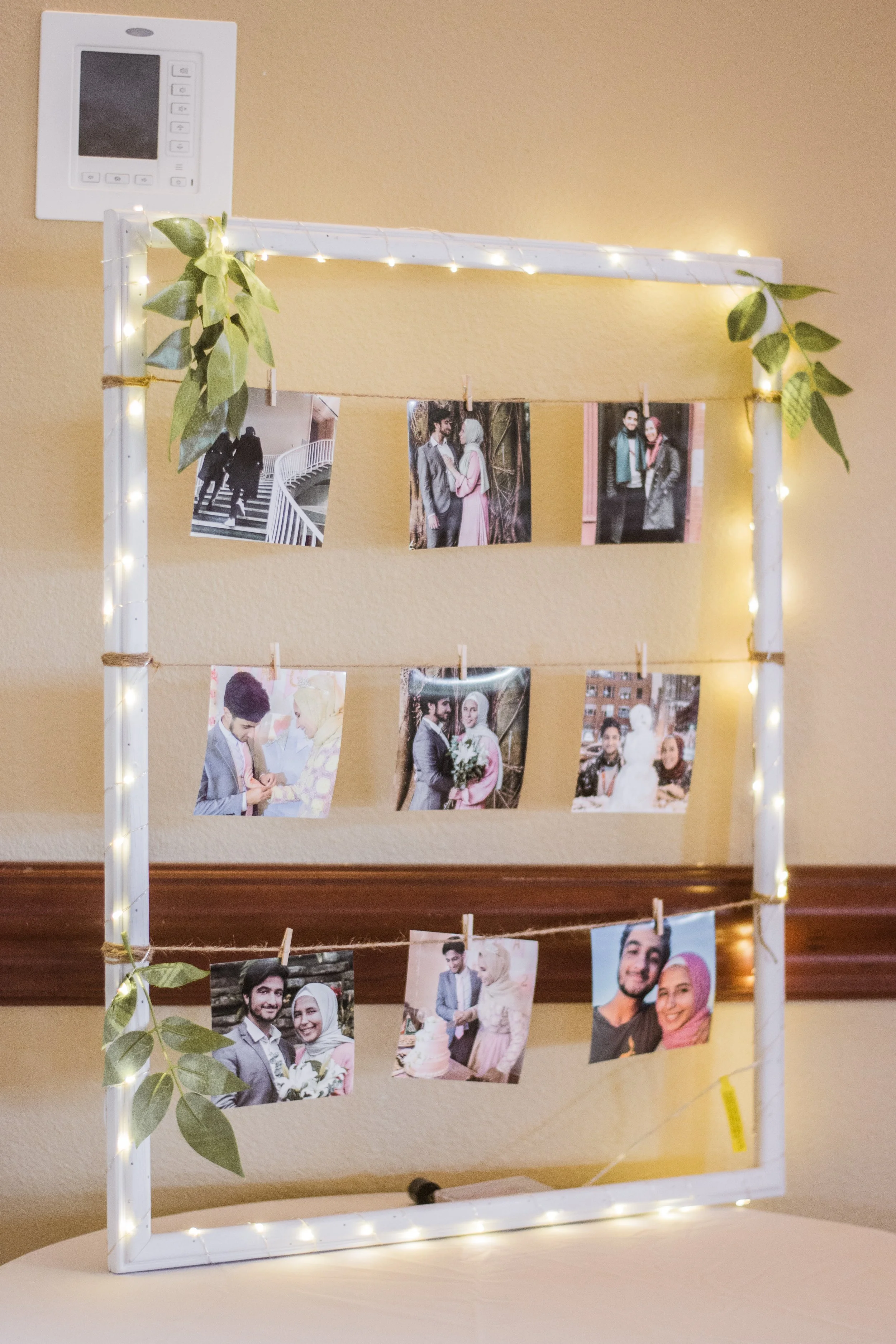 A DIY project we made by taking a frame from the thrift store, spray painting it, wrapping fairy lights around, and tying twine with mini clips to hold the pictures.