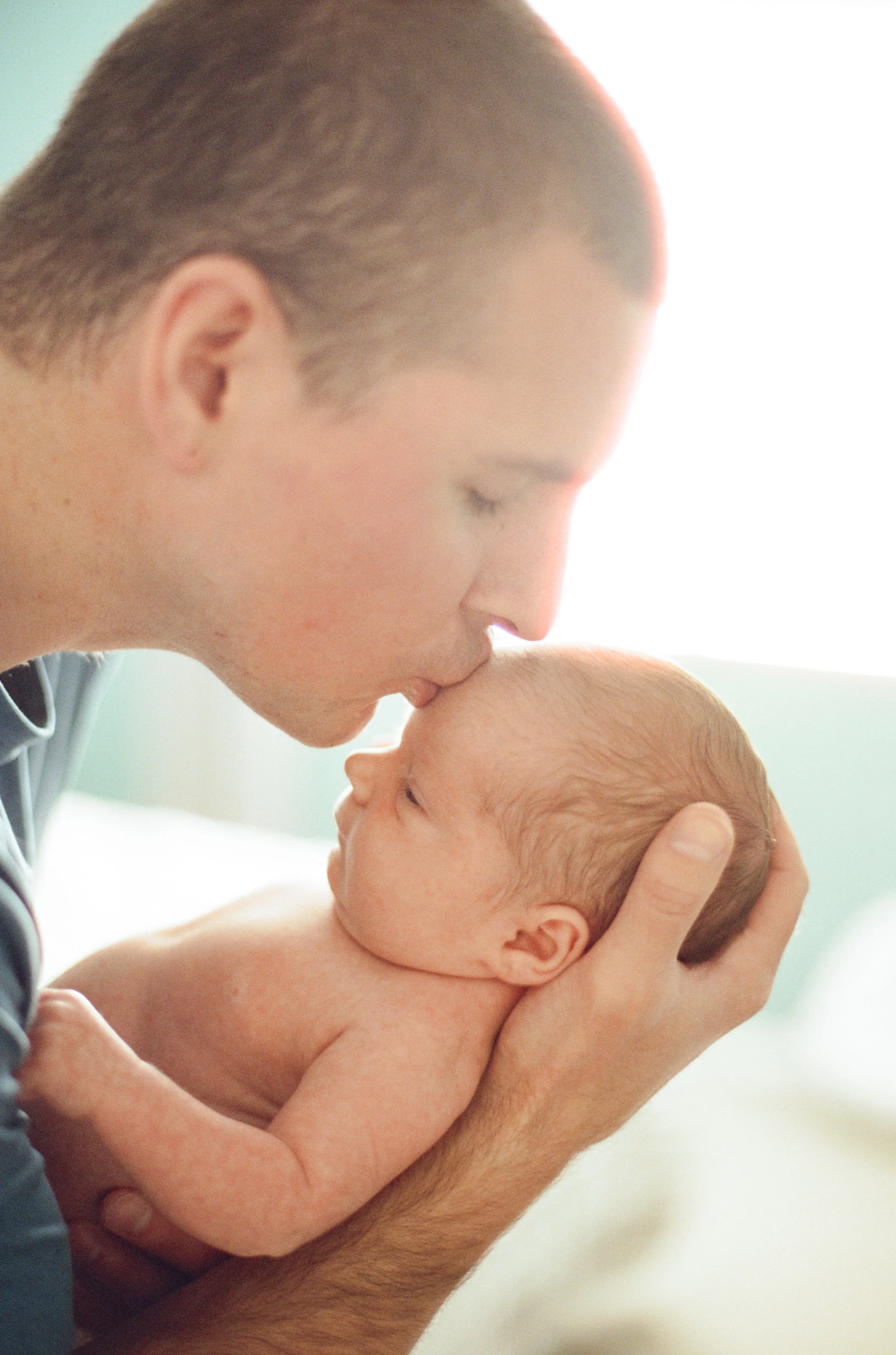 Father holding newborn during at-home session in natural, unposed moment