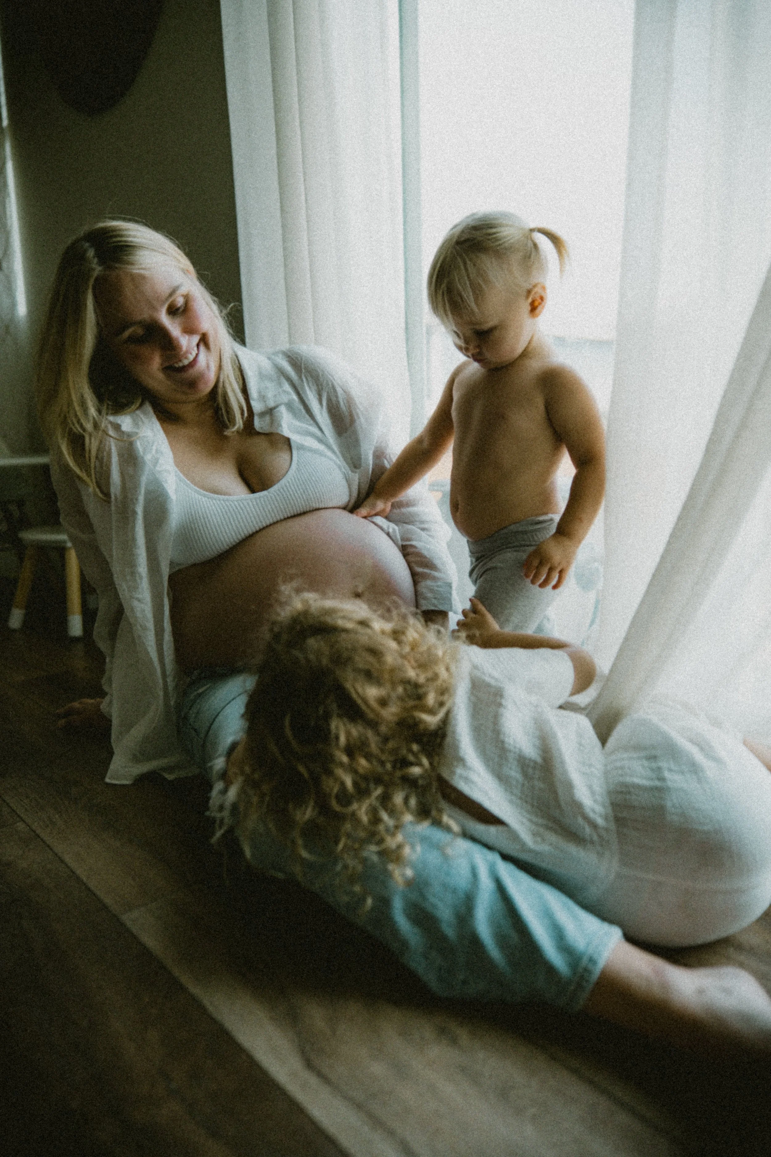 Daughters of seattle mom lounge with their mom and play with the baby in her belly.