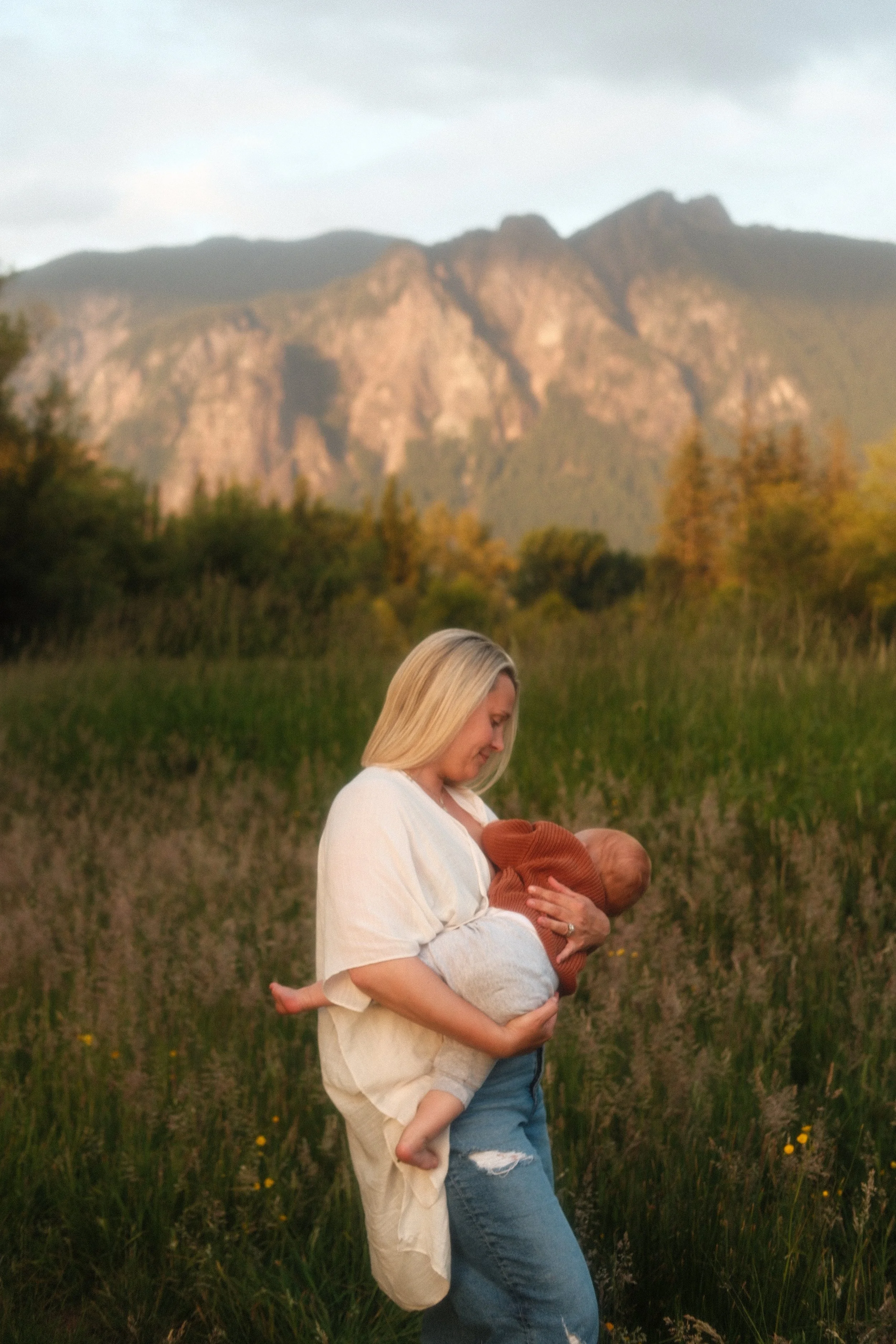 Mother breastfeeding and holding her baby with Cascade Mountain views in Seattle area family photos.