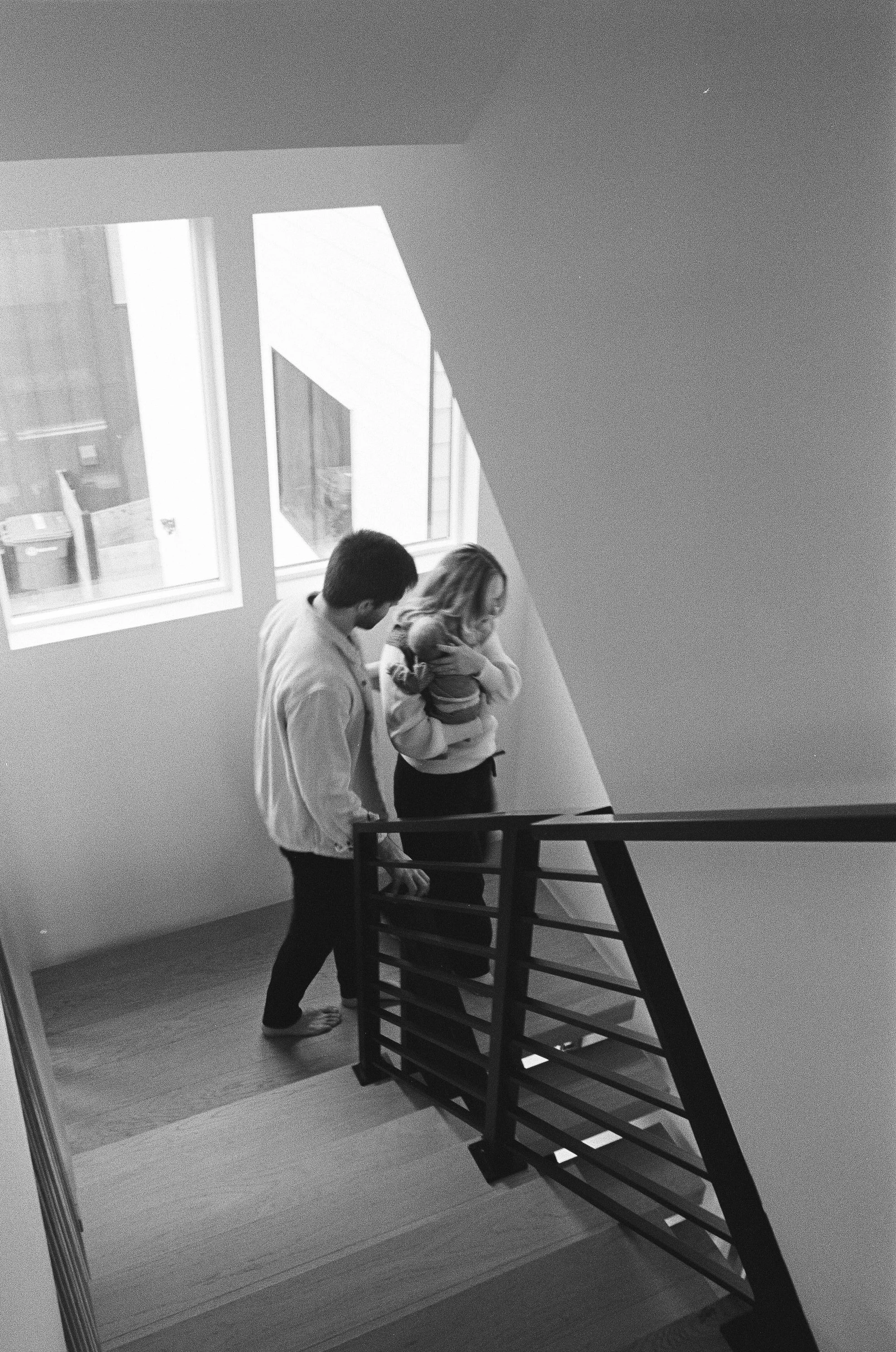 New parents of newborn baby boy walk down stairs in their Madrona Seattle home.