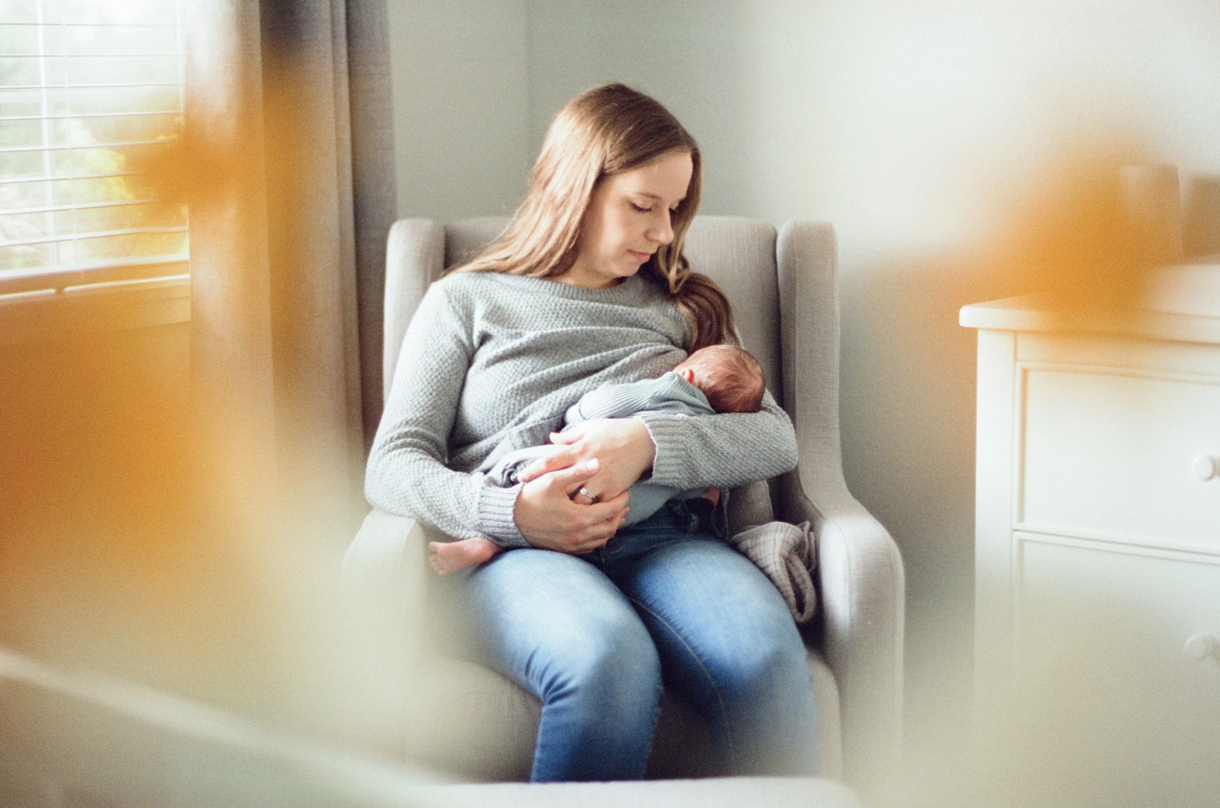 Film photo of baby being rocked in nursery with soft window light