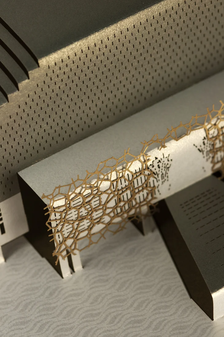 Detail shot of gold lattice laser-cut overlay and spot UV foil water pattern onto pearlescent white card.