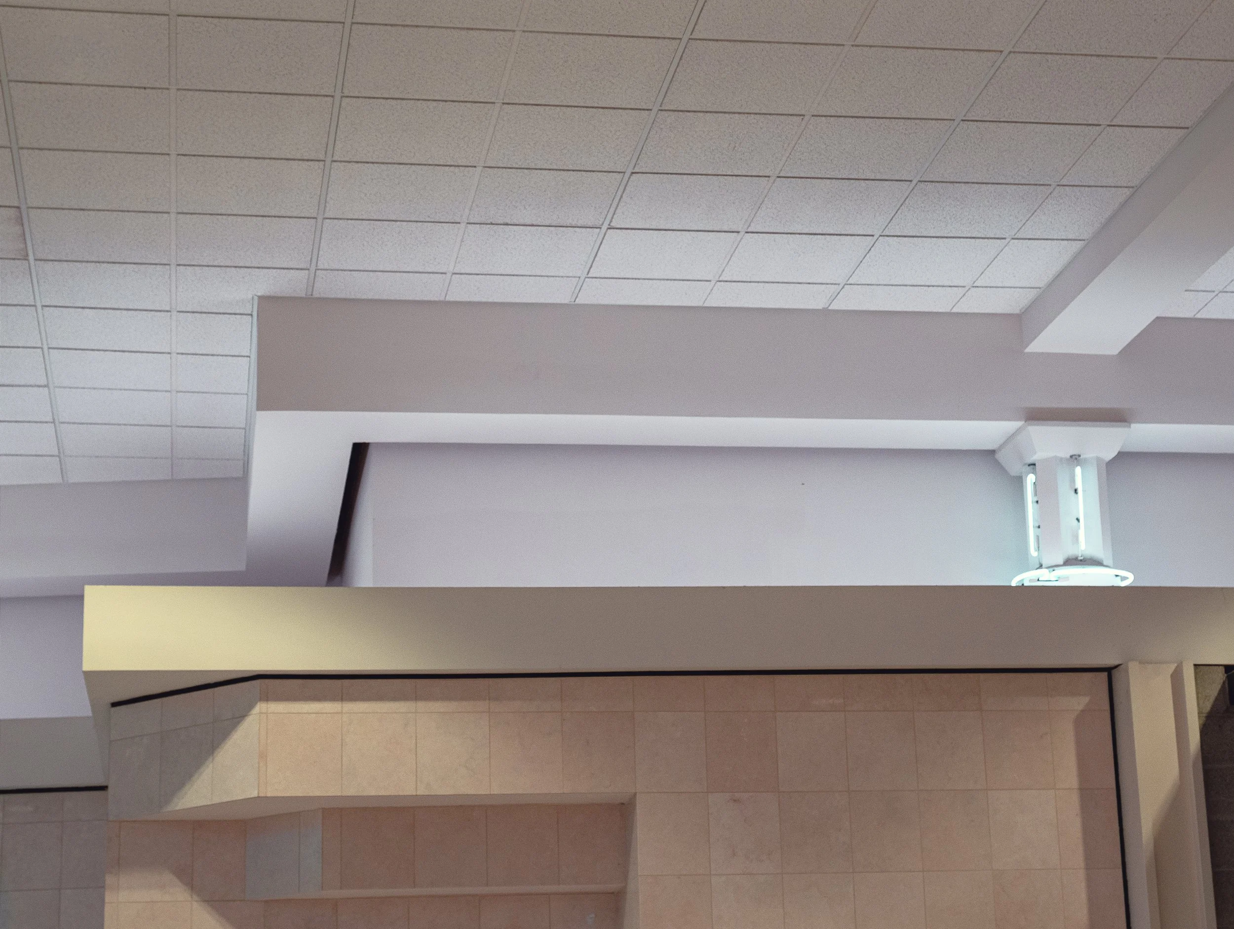 Indoor space with tiled ceiling and partial view of walls and counters.