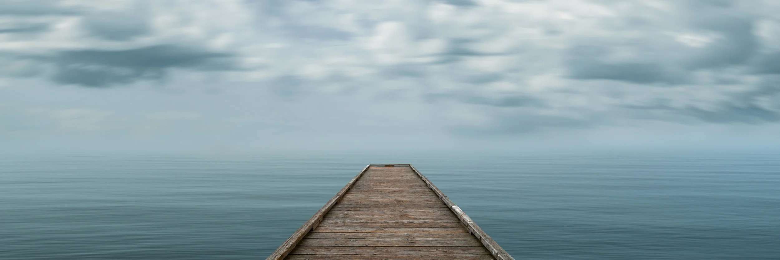 Edge of Solace is a panoramic photograph by Seattle based photographer, Jason Matias. The artwork is a center-weighted, blue-green seascape with a dock emerging from the center. The long exposure technique used creates a left to right motion blur of the water and clouds/sky. Jason's work can be seen by appointment at his art loft gallery in Bellevue, Washington, at fine art expos around the country and select galleries.