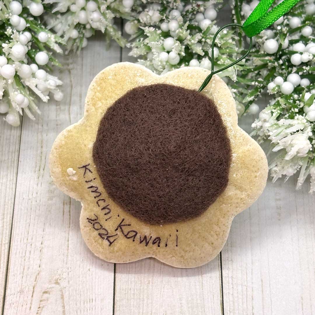 Back of a flower cookie ornament with felt and the words 'Kimchi Kawaii, 2024'.