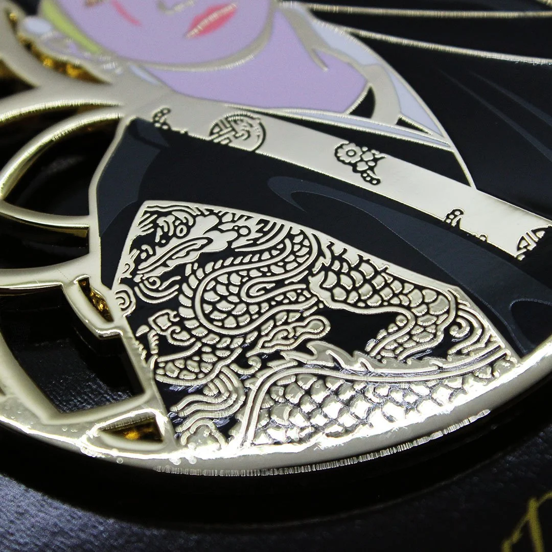 Detail from enamel pin of dragon design in gold metal.