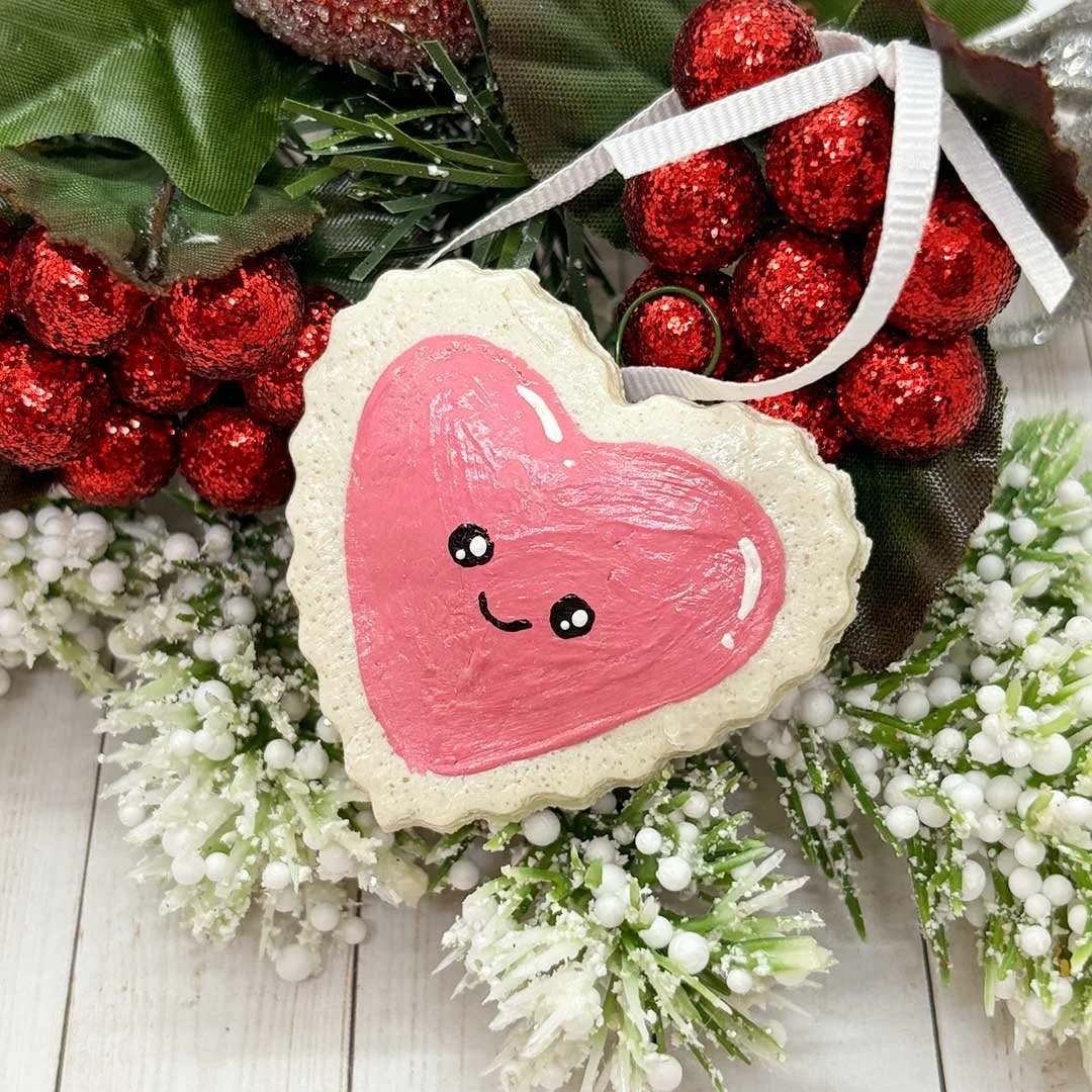 Smiling heart ornament with painted pink frosting.