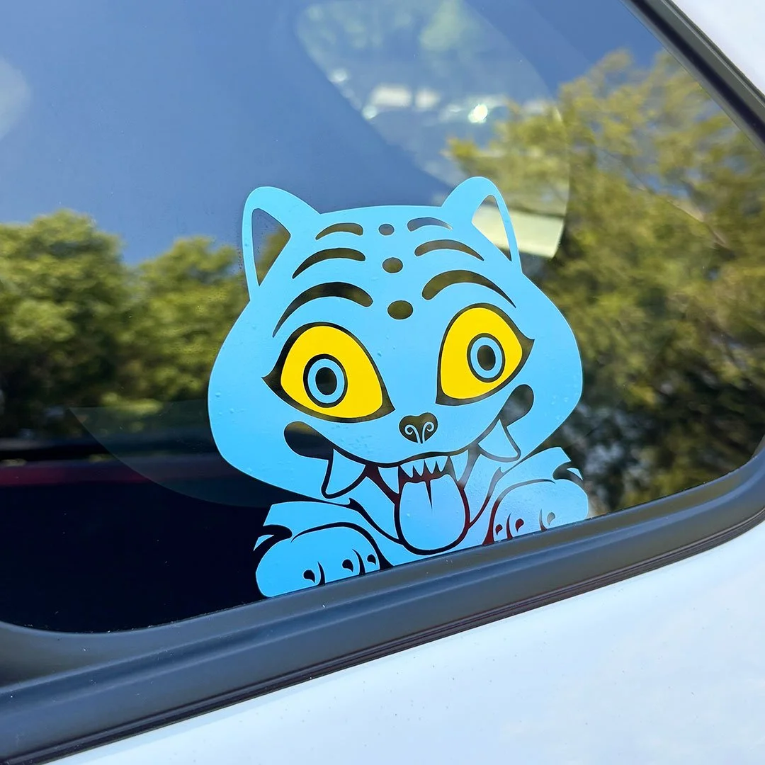 Sticker on a car window of a blue tiger with yellow eyes.