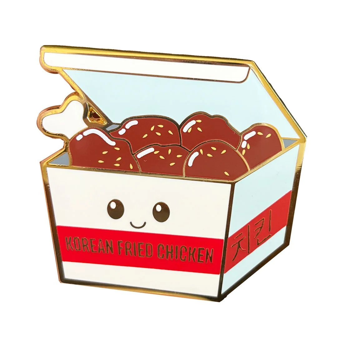 Enamel pin of a box of korean fried chicken.