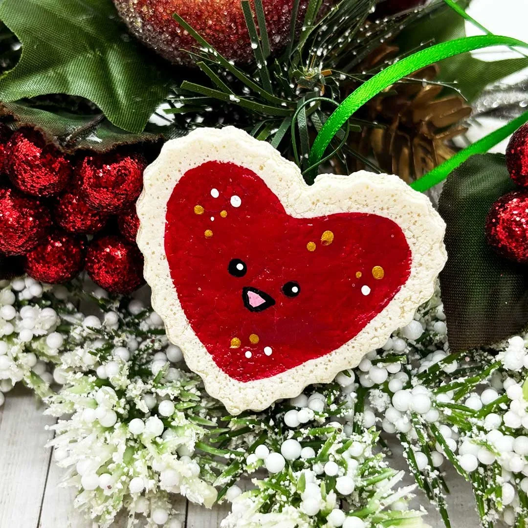 Smiling heart ornament with painted red frosting and sprinkles.