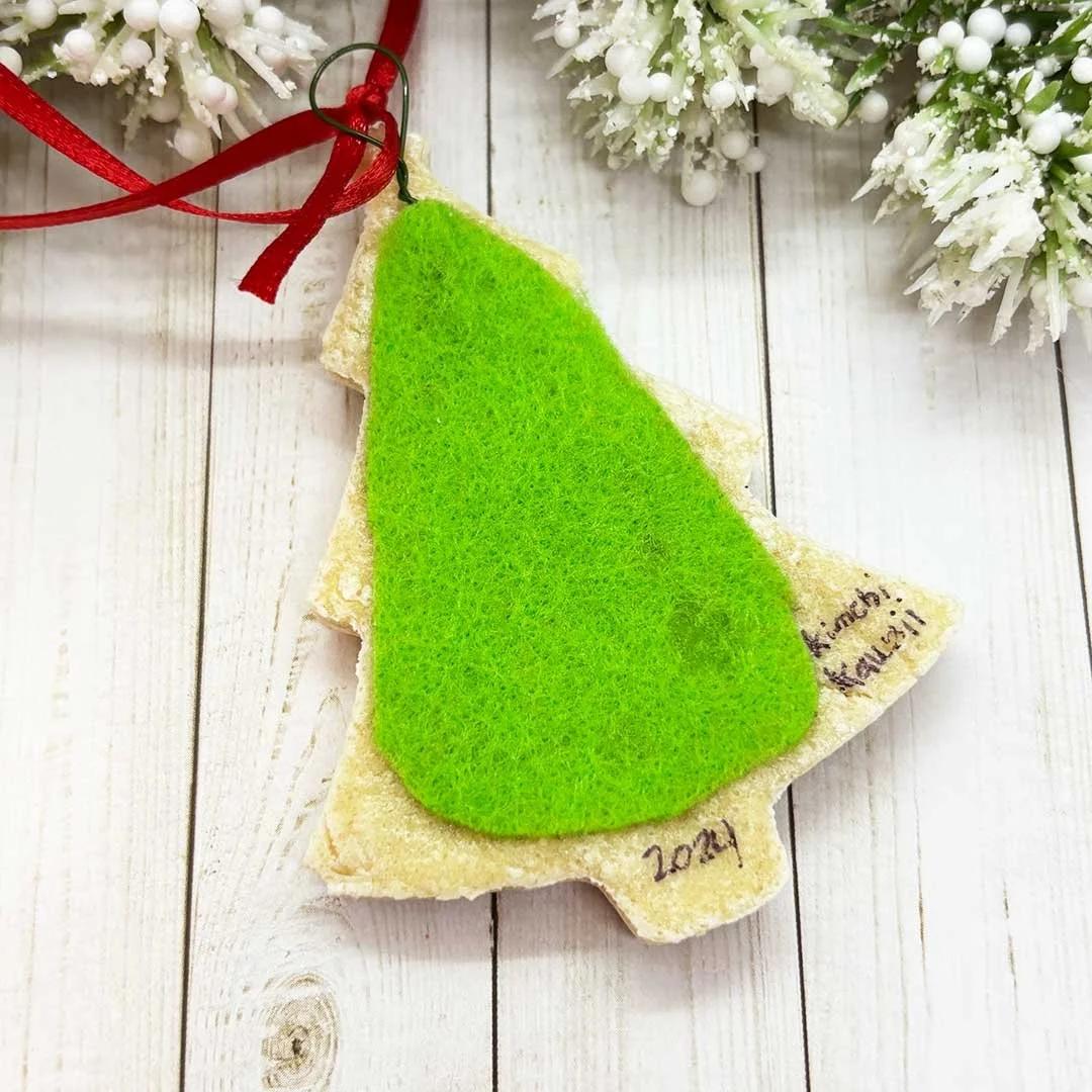 Back of a Christmas tree cookie ornament with green felt and the words 'Kimchi Kawaii, 2024'.