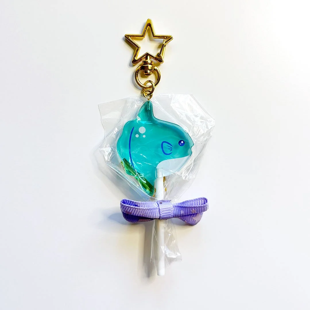 Blue acrylic mola mola lollipop charm with a gold clasp.