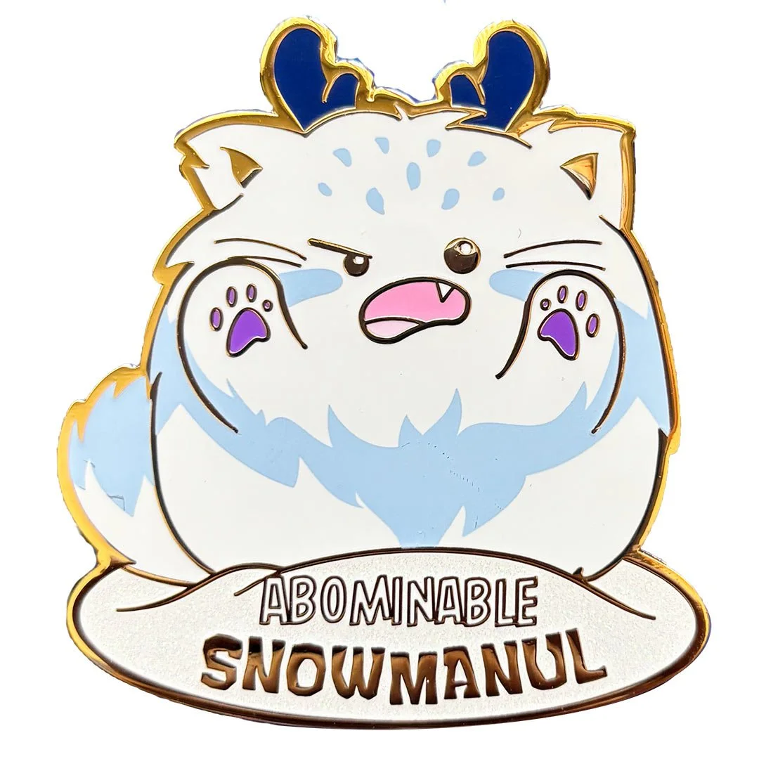 Enamel pin of a fluffy white and blue yeti cat. Text reads 'Abominable Snowmanul'.