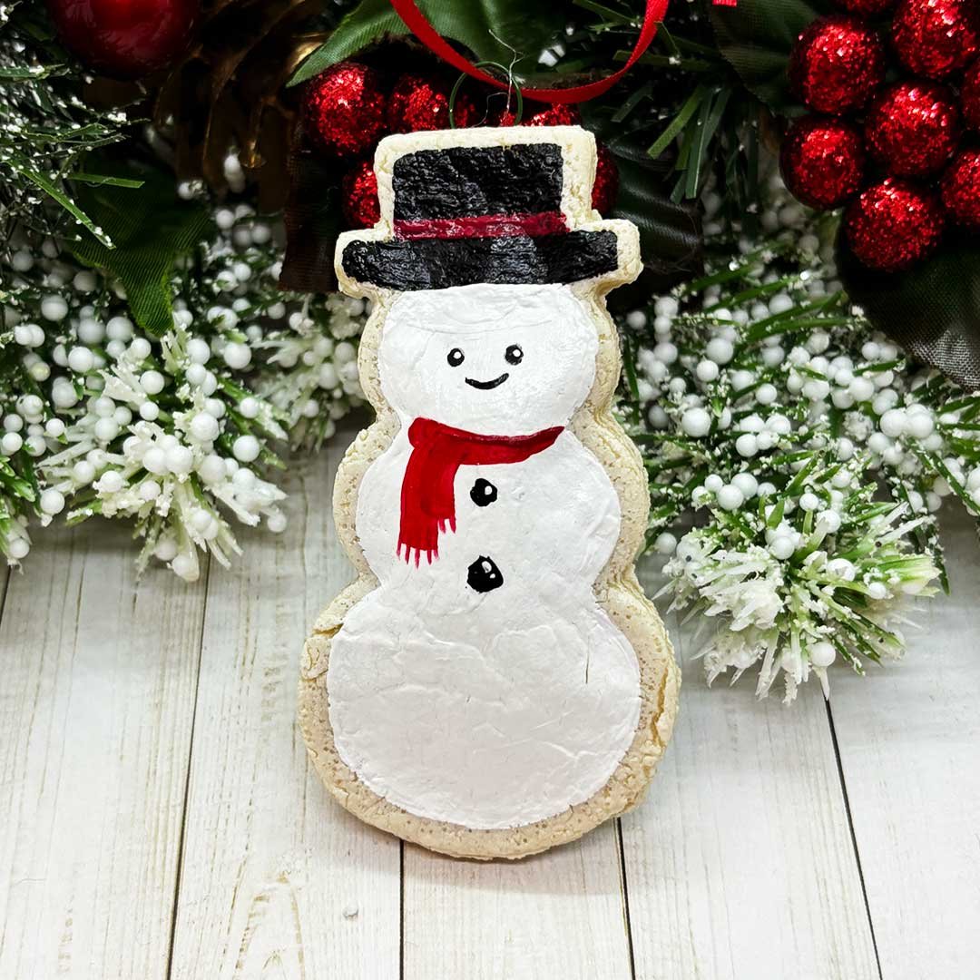 Cookie ornament of a snowman with a black hat and red scarf.