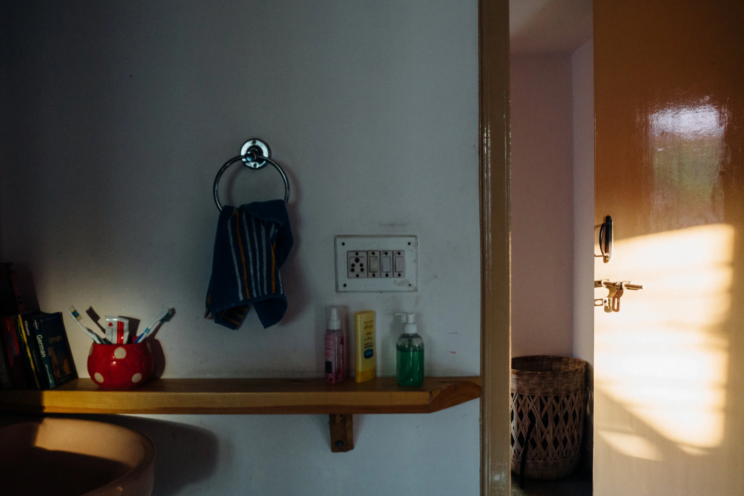 The door to the bedroom opens into the passageway to the living room. The washbasin is on the left of the passageway.