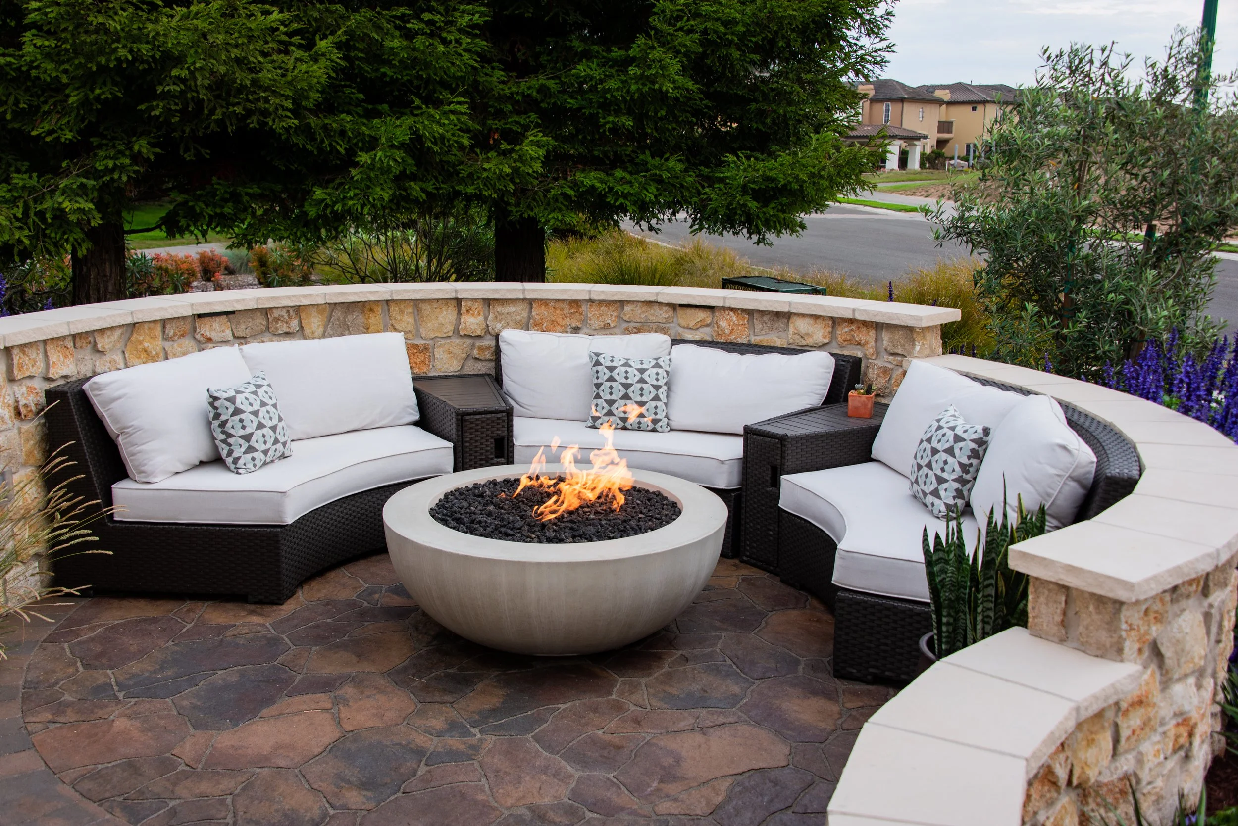 An image of a wrap around or circular outdoor seating area with a fire pit.