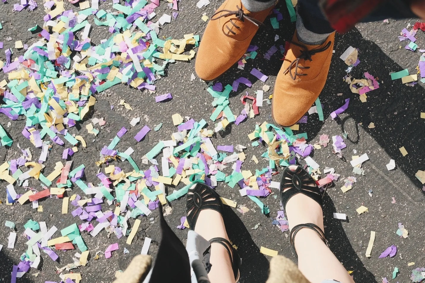 Looking down on feet of man and woman with multicolored confetti all around
