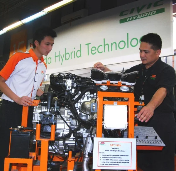 Cabas explaining to Chen how to diagnose the faults using the Honda Jazz engine simulator. Image form: zerotohundred.com