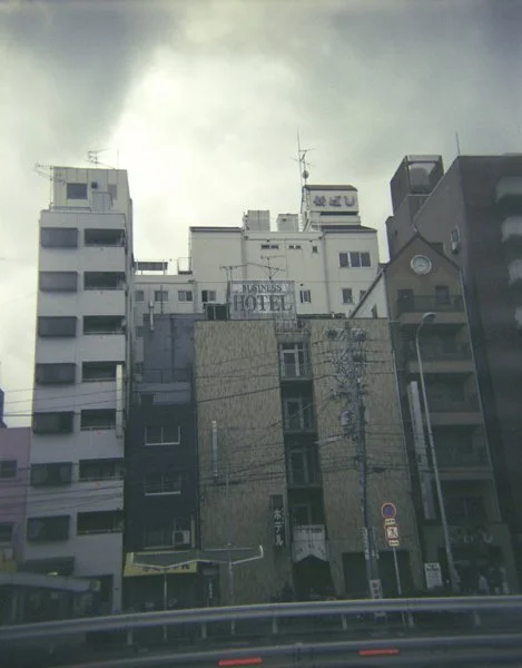 Vue de gratte-ciel en ville avec plusieurs bâtiments modernes, y compris un hôtel, sous un ciel nuageux.