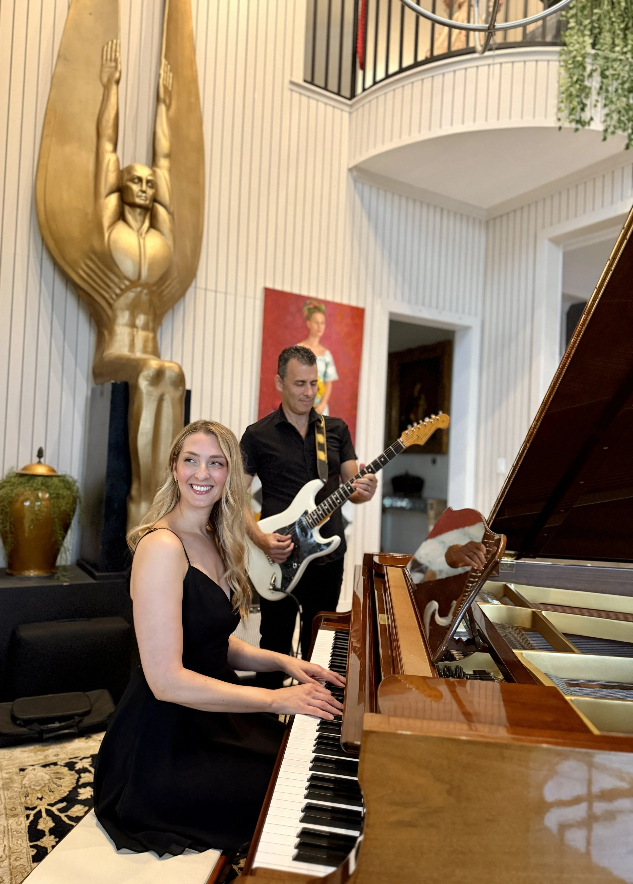 Blonde woman playing piano with brunette man playing guitar at a luxury private party in austin texas.