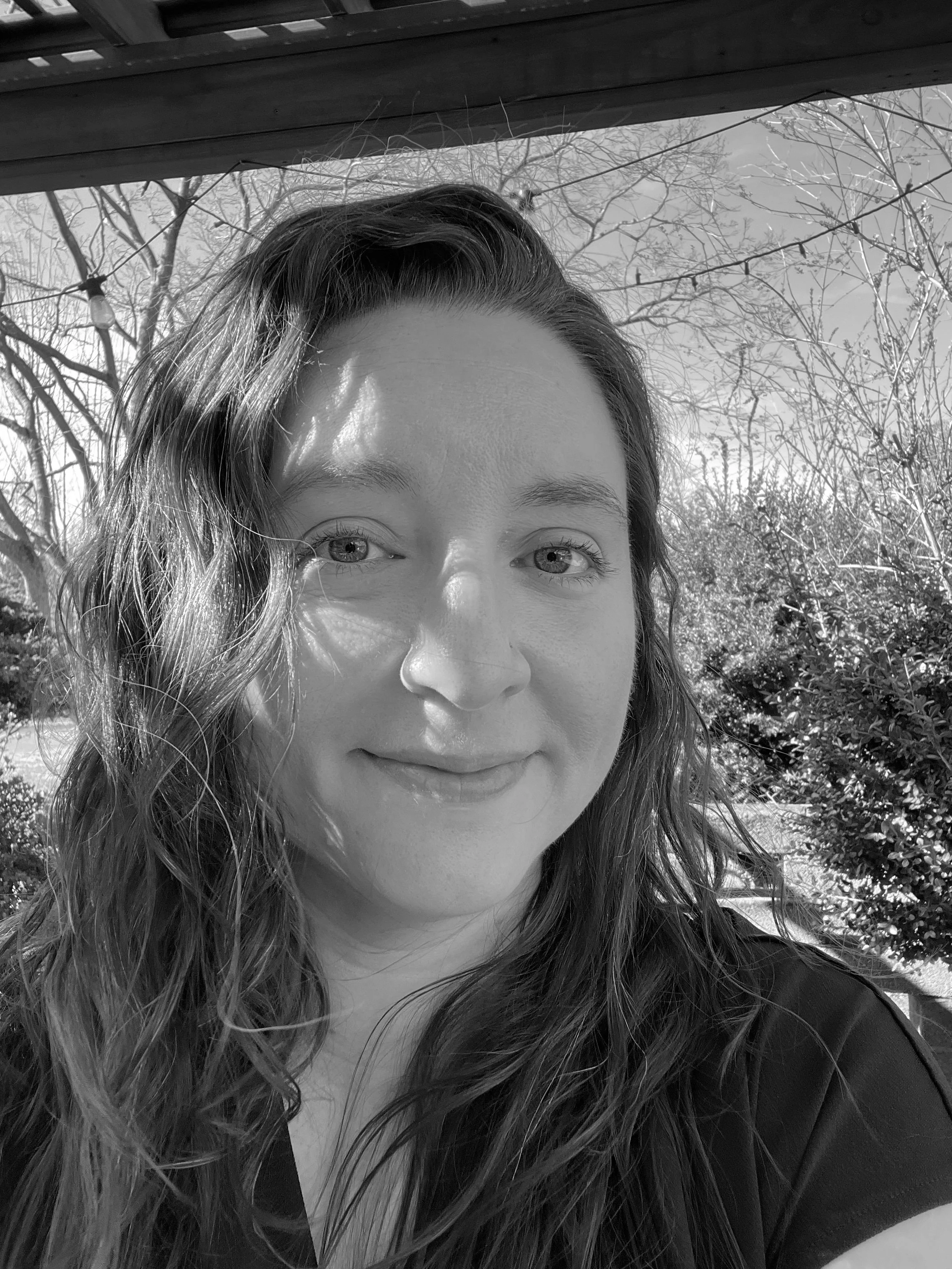 A woman with dark hair, with trees and sky behind her