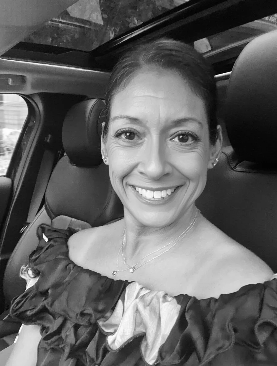 Black and white photo of a woman with off the shoulder shirt in car