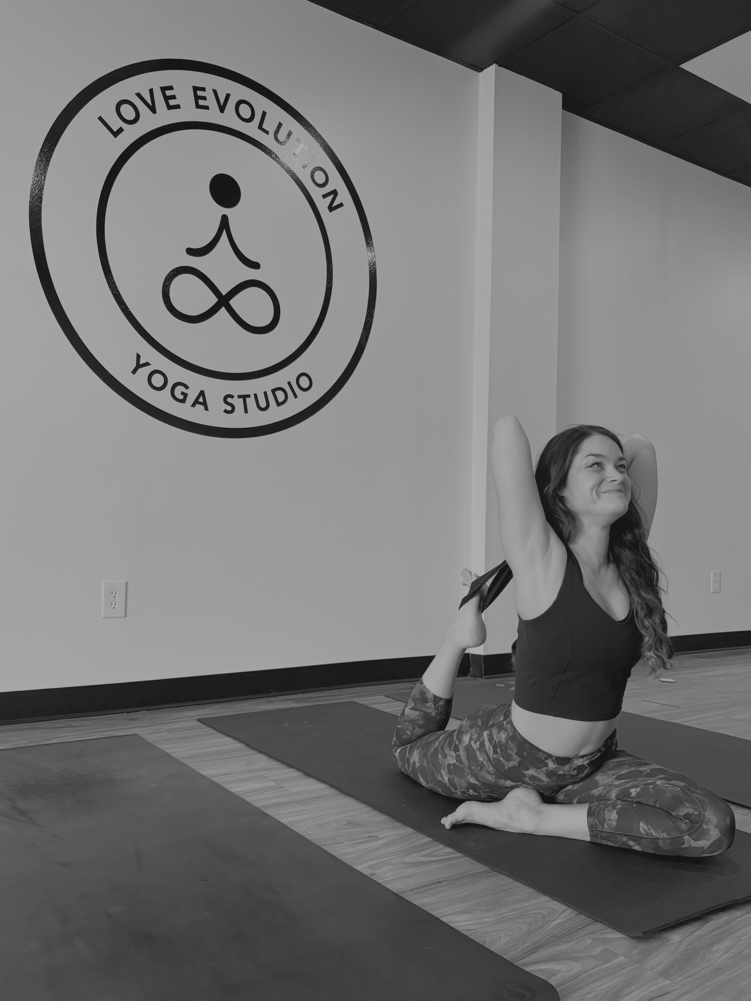 yoga teacher in studio showing king pigeon pose with prop.