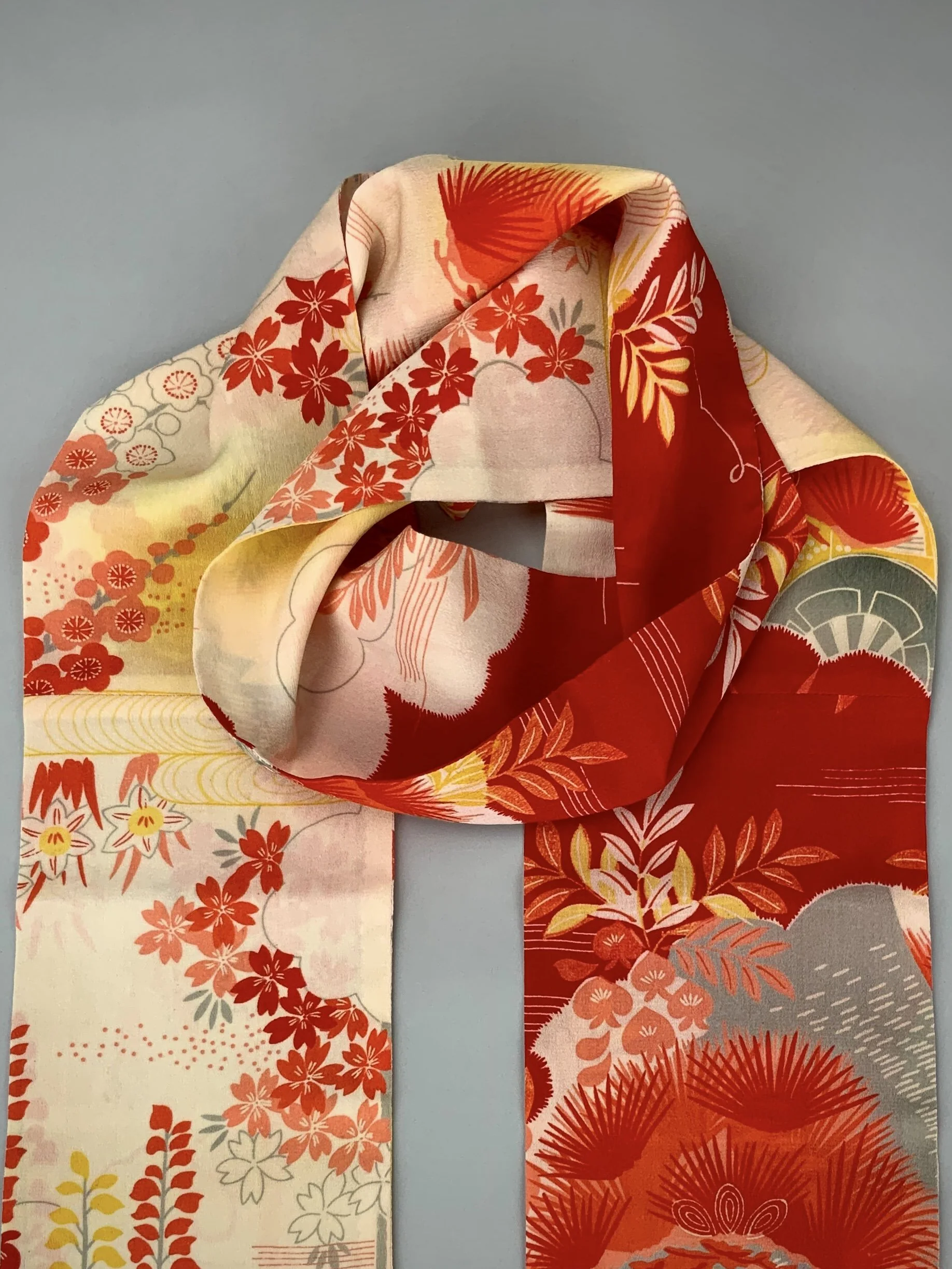Closeup of vibrant red and yellow scarf with printed blossom design, handmade from repurposed Japanese kimono crepe silk by Kirsty Chivers